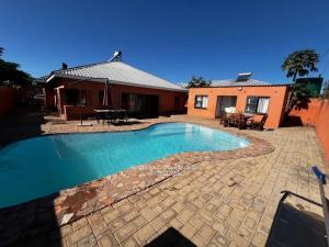 a swimming pool in front of a house at Lhondeh Apartments in Livingstone