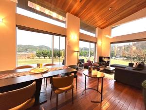 a living room with a table and chairs and large windows at The SATOYAMA HILLS FK1 in Futtsu