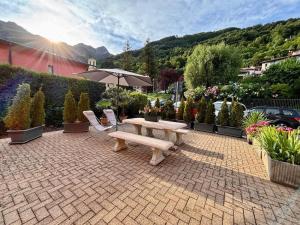 a patio with a bench and a table and some plants at Due laghi – Studio Apartment with Pool in Porlezza