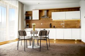 a kitchen with white cabinets and a table and chairs at Donovaly Residence Apartment 111 in Donovaly