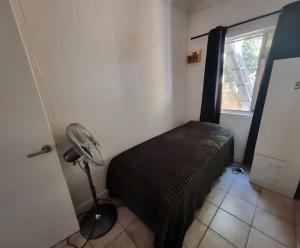 a room with a bed with a lamp and a window at Backpackers Homestay 21-36 yrs ONLY in Caloundra
