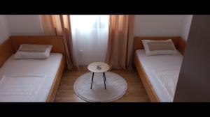 two beds in a room with a table between them at Vinarija Andjusic in Dračevo +8 photos