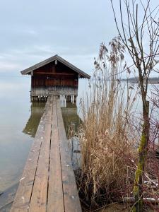 a wooden dock in the water with a building on it at Stodl Living Chiemsee in Grabenstätt +25 photos