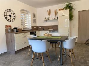 a kitchen with a table and some white chairs at Stodl Living Chiemsee in Grabenstätt