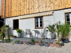 a patio with two chairs and a table and plants at Stodl Living Chiemsee in Grabenstätt