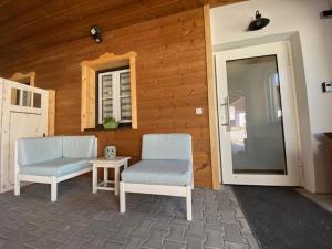 a patio with two chairs and a table and a door at Stodl Living Chiemsee in Grabenstätt