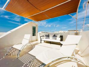 a balcony with white chairs and a bench on a roof at Hotel Ca S'Arader Turismo de Interior in Ciutadella