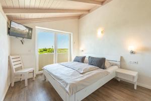 a white bedroom with a bed and a window at Ferienhaus Seestern in Dagebüll