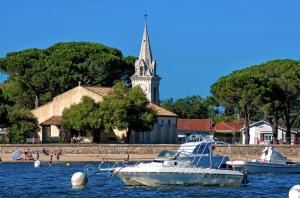 two boats in the water in front of a church at villa Moana andernos in Andernos-les-Bains