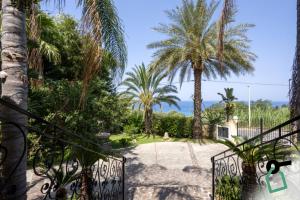 a gate to a garden with palm trees at Hotiday Tropea Parghelia in Tropea