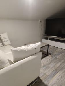 a living room with a white couch and a flat screen tv at Omenapolun Onni in Taipalsaari