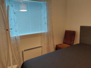 a bedroom with a bed and a window with a chair at Omenapolun Onni in Taipalsaari