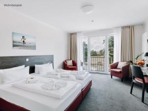 a hotel room with a large bed and two chairs at Hotel Bloemfontein in Borkum
