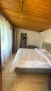 a woman standing in a bedroom with a large bed at Cabana din vale in Cioclovina