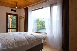a bedroom with a bed and a large window at Cabana din vale in Cioclovina