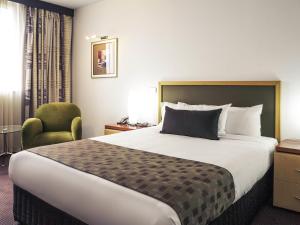 a hotel room with a large bed and a chair at Mercure Albury in Albury