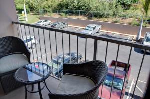 a balcony with two chairs and a table and a view of a parking lot at Pacific Shores B303 in Kihei