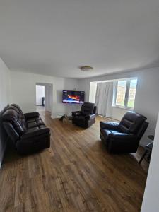 a living room with two leather chairs and a flat screen tv at Luca apartament 3 camere in Băile Herculane