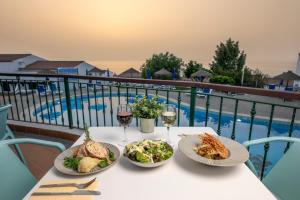 a table with three plates of food and glasses of wine at Ona Las Rosas in Puerto de Santiago