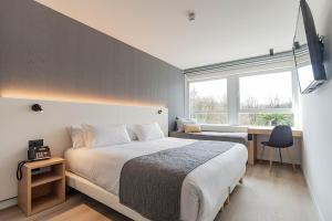 a bedroom with a bed and a desk and a window at Hotel Distrito Oeste by Limehome in San Sebastián