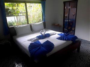 a bed with blue bows on it with a window at D&K Smiley Phuket Resort in Rawai Beach +35 photos