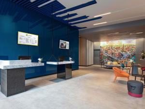 a lobby with a blue wall with a painting at ibis Styles Bangkok Sukhumvit 4 in Bangkok