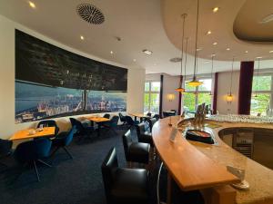 a restaurant with tables and chairs and a large screen at Hotel Belmondo Leipzig Airport by Mayburgh in Wiedemar