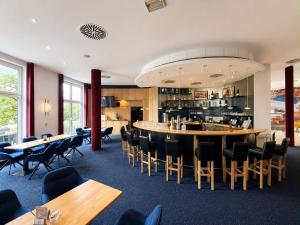 a restaurant with a bar and tables and chairs at Hotel Belmondo Leipzig Airport by Mayburgh in Wiedemar