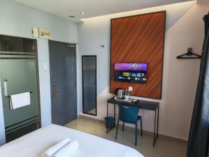 a hotel room with a desk and a tv on the wall at Hotel 99 Kota Kemuning in Shah Alam
