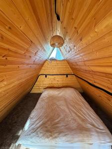a small bed in a wooden room with a light at Glamping baytik in Verkhnyaya Alaarcha