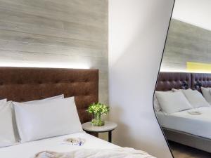 ein Schlafzimmer mit zwei Betten und einem Spiegel in der Unterkunft Pullman Santiago El Bosque in Santiago