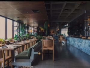 a restaurant with wooden tables and chairs and windows at Novotel Medellin El Tesoro in Medellín