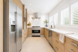 a kitchen with wooden cabinets and a stainless steel refrigerator at Kos Place in Blairgowrie by Ready Set Stay in Blairgowrie