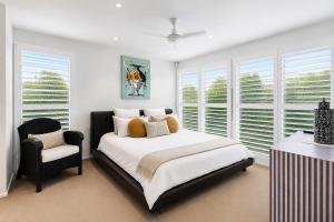 a bedroom with a bed and a chair and windows at Kos Place in Blairgowrie by Ready Set Stay in Blairgowrie
