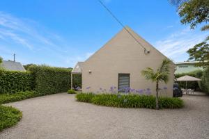 a white house with a palm tree and purple flowers at Kos Place in Blairgowrie by Ready Set Stay in Blairgowrie