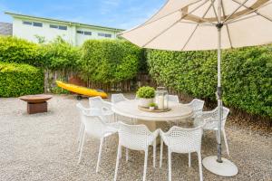 a table with white chairs and an umbrella at Kos Place in Blairgowrie by Ready Set Stay in Blairgowrie