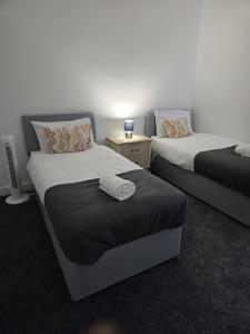 a room with two beds and a night stand at Modern 3BDR Home l Sleeps 5 l Free Parking l Close to Train station and Shops in Worksop