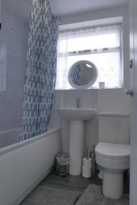 a bathroom with a sink and a toilet and a window at Modern 3BDR Home l Sleeps 5 l Free Parking l Close to Train station and Shops in Worksop +19 photos