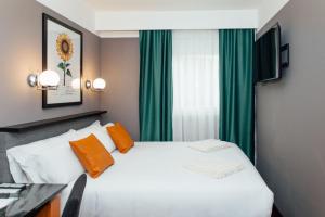 1 dormitorio con cama blanca y cortinas verdes en Hotel Malcom and Barret en Valencia