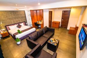 a room with a bed and a couch and a tv at Neelagiri Heritage Hotel - Near Calicut Railway Station in Kozhikode