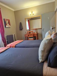 a bedroom with two beds and a table and a mirror at The Blue Swallow in Kaapsehoop +4 photos