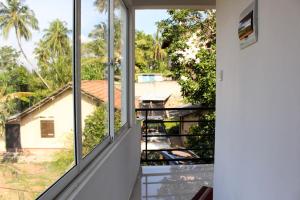 a room with windows looking out at a house at Sandu Guest in Mirissa