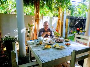a man sitting at a table with food on it at Villa Akeinya in Matara