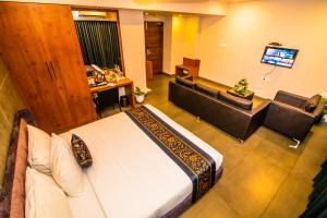 a room with a bed and a couch and a television at Neelagiri Heritage Hotel - Near Calicut Railway Station in Kozhikode +19 photos