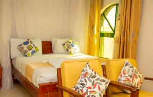 a bedroom with two beds and two yellow chairs at Comfy Inn Hotel in Eldoret +33 photos
