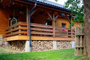 a wooden house with a deck and fire logs at Pod Dzwonkiem in Jasienica