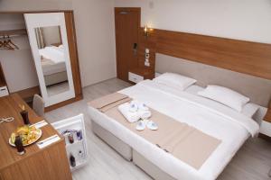 a bedroom with a large white bed with a mirror at FAVORİTE Hotel in Söğütlü