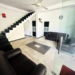 a living room with a black couch and stairs at Villa Akeinya in Matara
