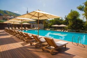 a row of chairs and umbrellas next to a swimming pool at The Telegraph Hotel - The Leading Hotels of the World in Tbilisi City