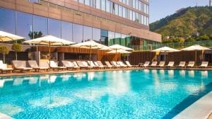a swimming pool with chairs and umbrellas next to a building at The Telegraph Hotel - The Leading Hotels of the World in Tbilisi City
